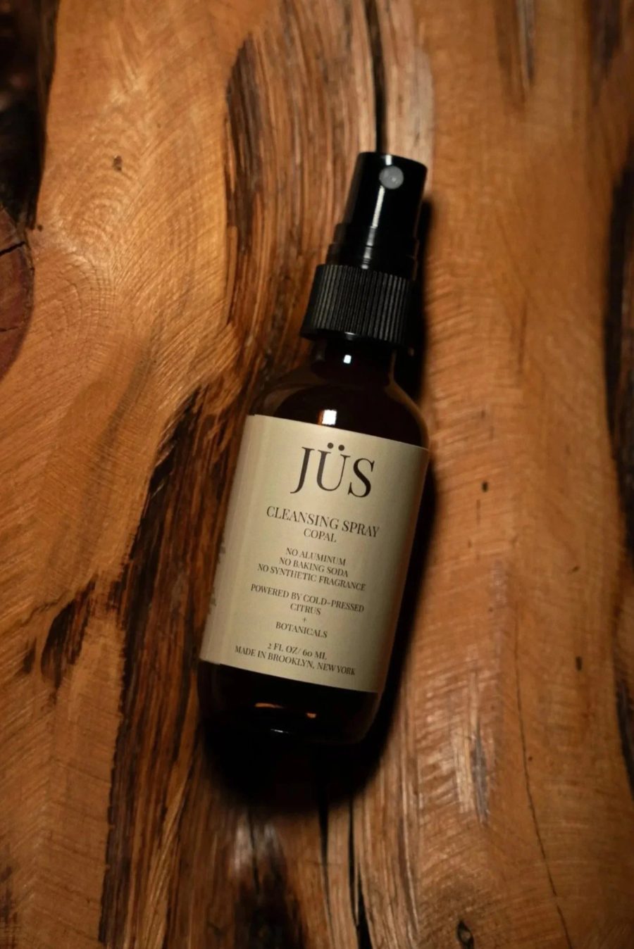 JÜS Copal Cleansing Spray bottle on carved wood