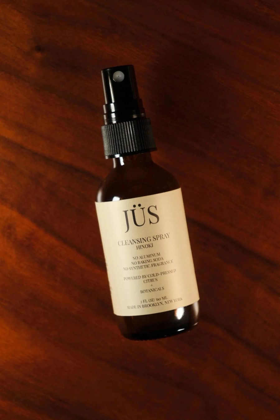 JÜS Hinoki Cleansing Spray bottle on hinoki wood